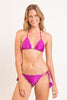A smiling woman models a bright magenta ruffled bikini featuring a triangle top and matching side-tie bottoms.